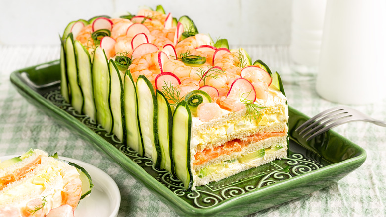 Frosted sandwich loaf garnished with cucumbers, dill, and radishes