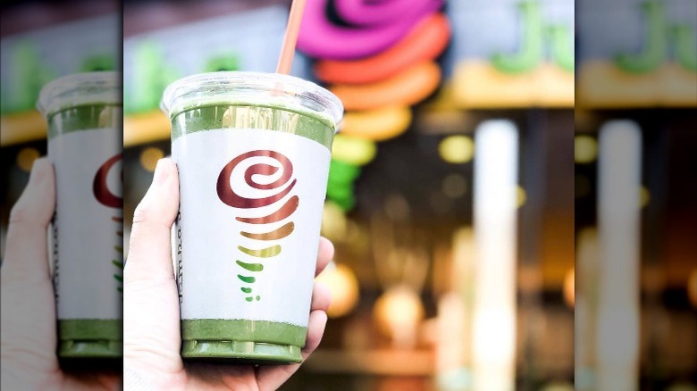 Someone holds a green Jamba Juice smoothie