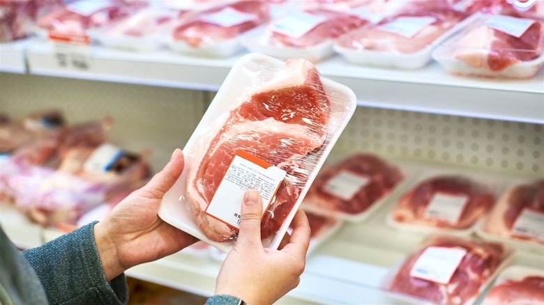 Grocery shopper holding packaged pork