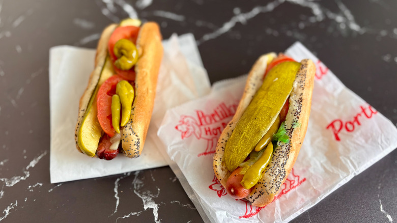 Two Chicago-style hot dogs on parchment wrappers