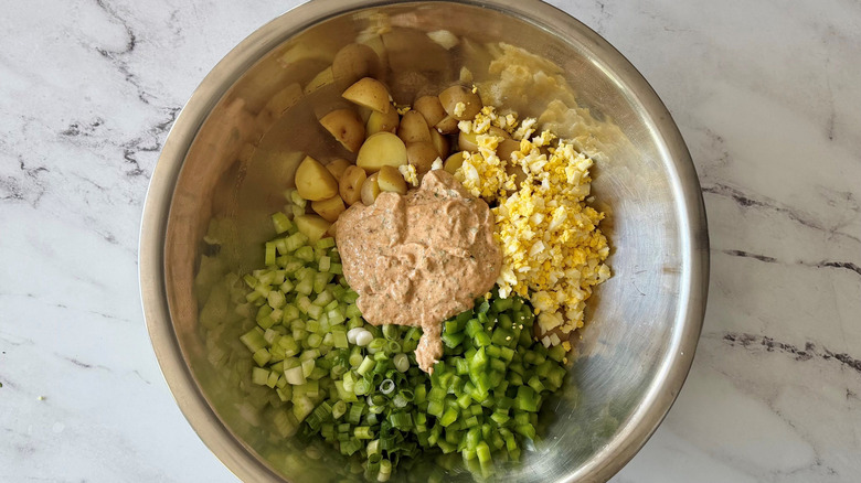 Unmixed potato salad in bowl with dressing