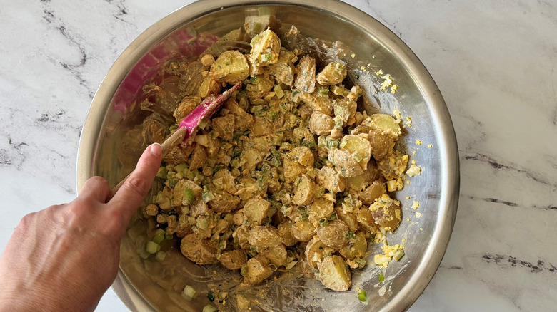 Mixing Cajun potato salad in bowl