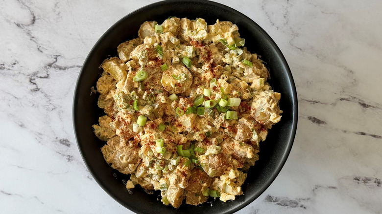 Cajun potato salad in bowl topped with green onions