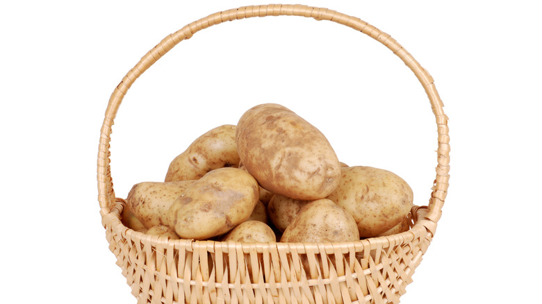 Russet potatoes in a handled wicker basket.