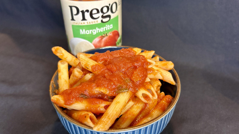 Saucy pasta in a bowl with the Prego Margherita sauce jar behind it