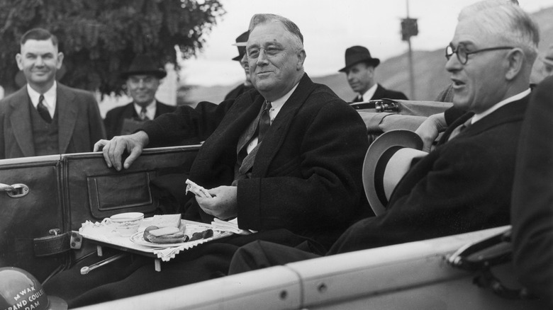 Franklin D. Roosevelt eating sandwiches in a convertible