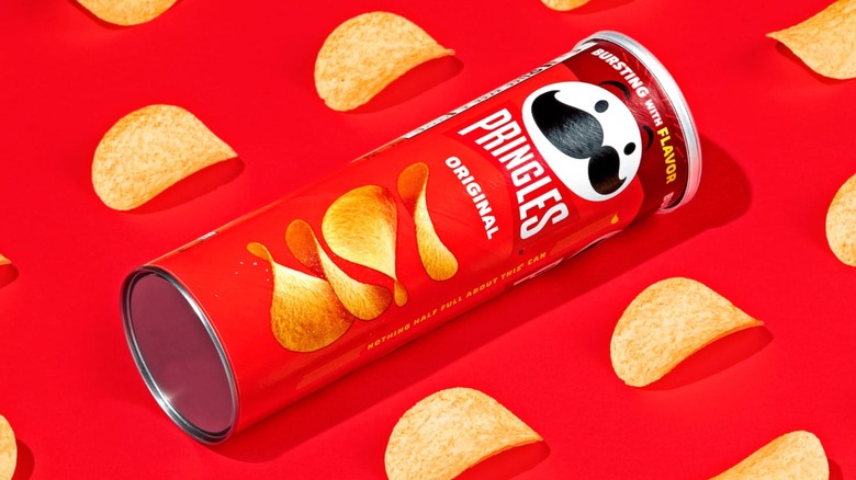 A can of Pringles on its side surrounded by chips