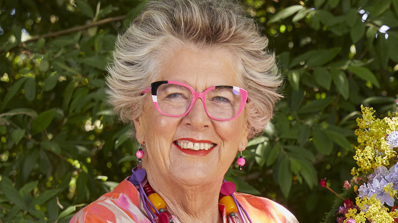 Prue Leith smiling outside in pink glasses