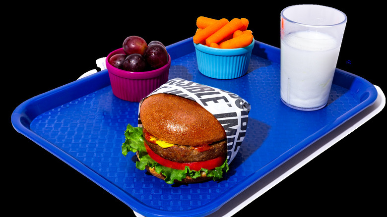 school lunch tray with milk, grapes, carrots, and impossible burger