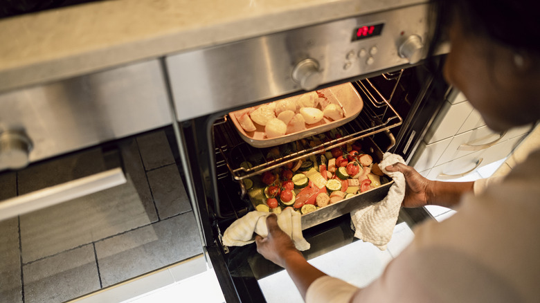 Person putting vegetables in the oven