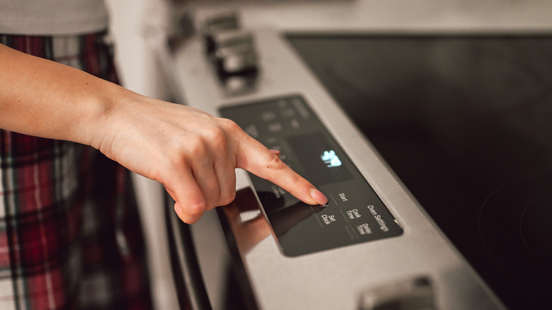 Person pressing buttons on a modern stovetop