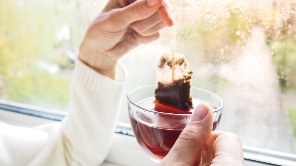 Woman making a cup of tea in front of a window