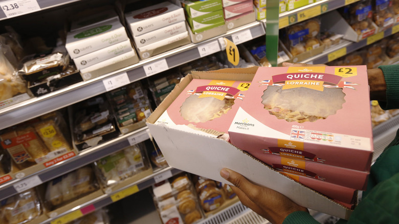 person holds quiche in grocery store