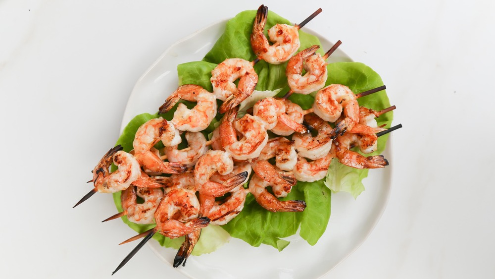 grilled shrimp on skewers with lettuce and white plate