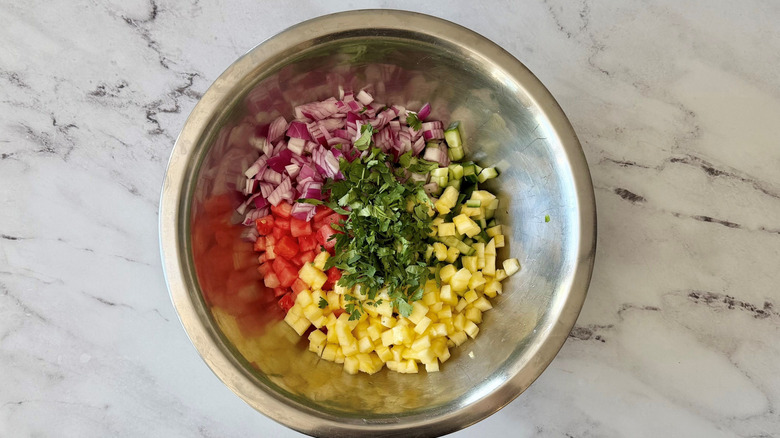 Diced watermelon, pineapple, red onion, cucumber, and cilantro in bowl