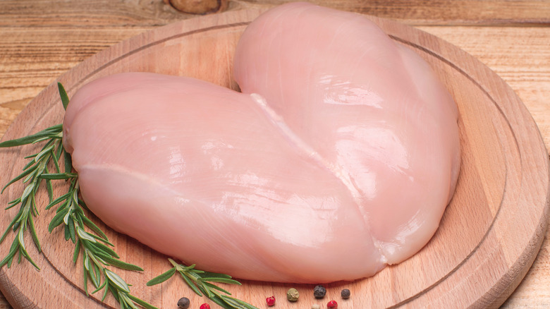 Butterfly chicken breast on a wooden board with rosemary sprigs on the side