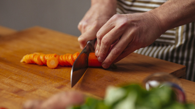 A home cook cutting a carrot