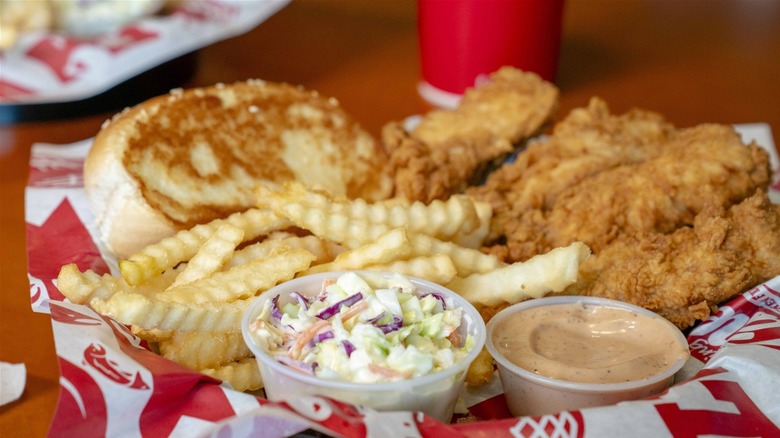 Raising Cane's combo on a tray with chicken fingers, Texas toast, fries, coleslaw, and Cane's sauce