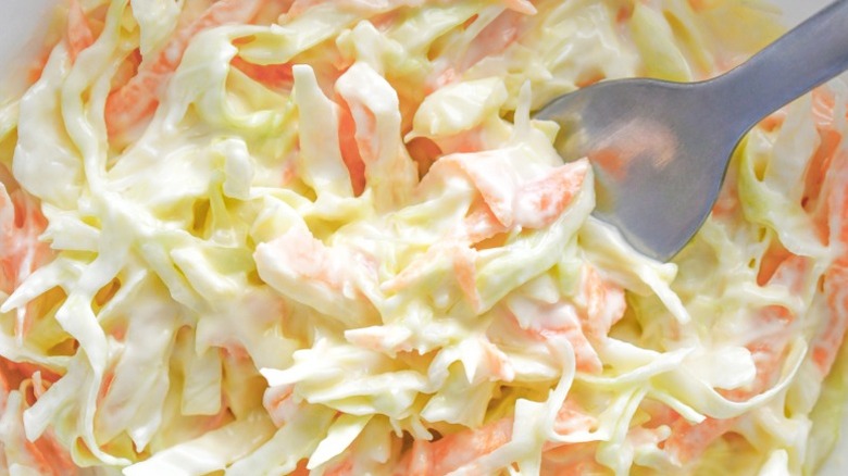 Close-up of mayo-dressed cabbage and carrot coleslaw with a fork in it
