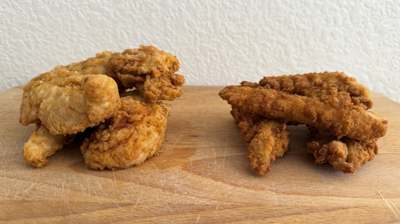 Chicken tenders from Raising Cane's and Chick-fil-A stacked into small piles on a cutting board