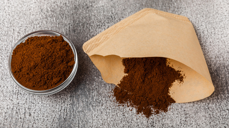 A coffee filter next to a container of coffee grounds.