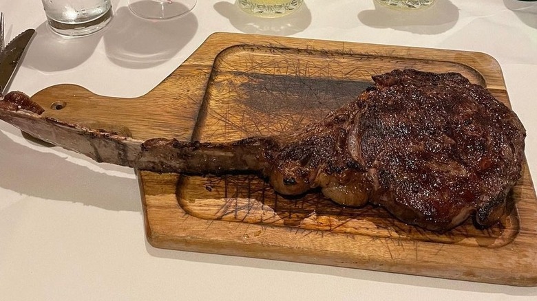 The Palm restaurant ribeye steak on a plate in front of several alcaholic beverages