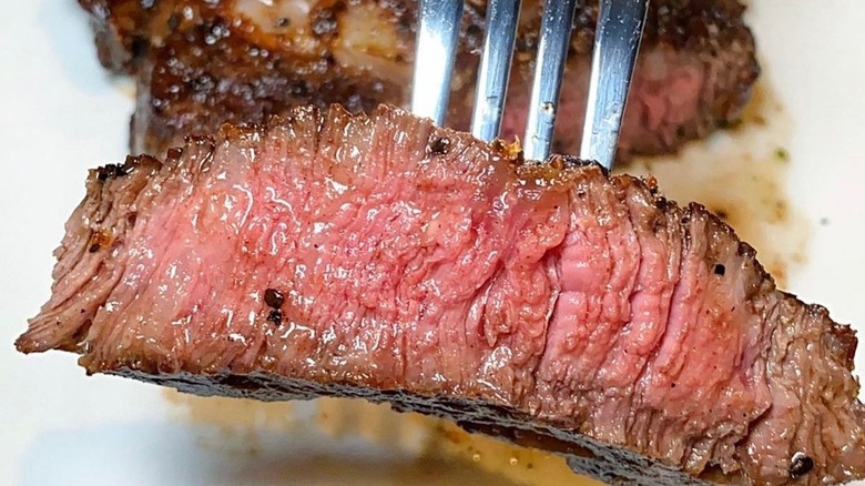 Fleming's prime bone-in ribeye steak on a plate with a bite on a fork