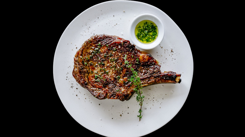 Ribeye steak on a plate with a dip and a black background