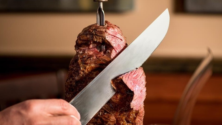 knife slices through skewered steak