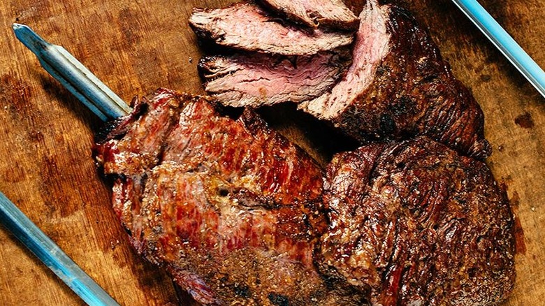 skewered steak sits atop a wooden table