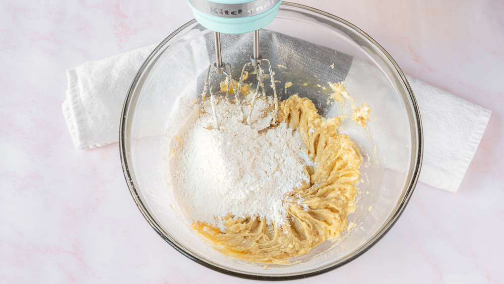 adding flour to dough to raspberry bars