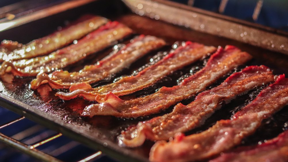 Close up of bacon cooking in an oven on a baking sheet.