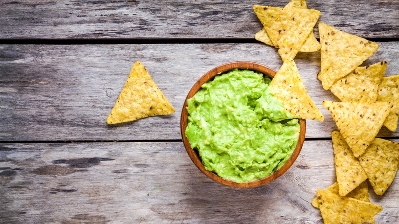 A bowl of guacamole with nacho chips