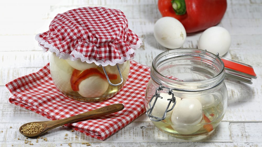 Two jars of pickled eggs on tablecloth