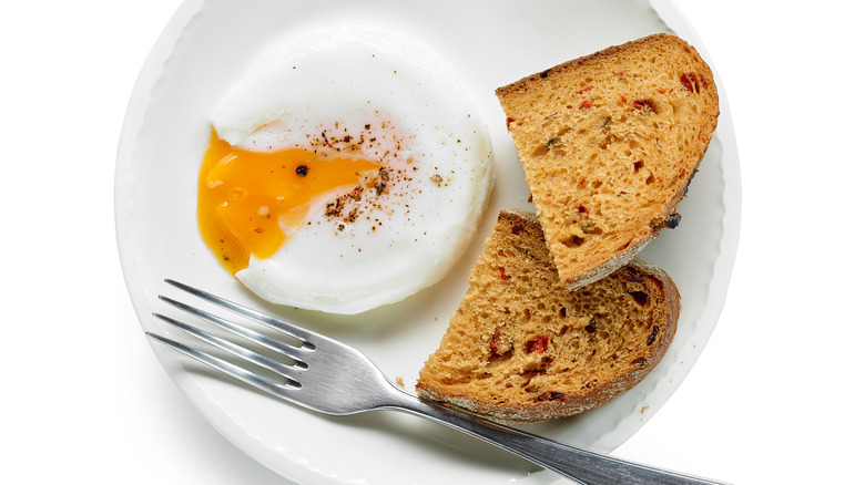 Poached egg and toast on white plate with fork