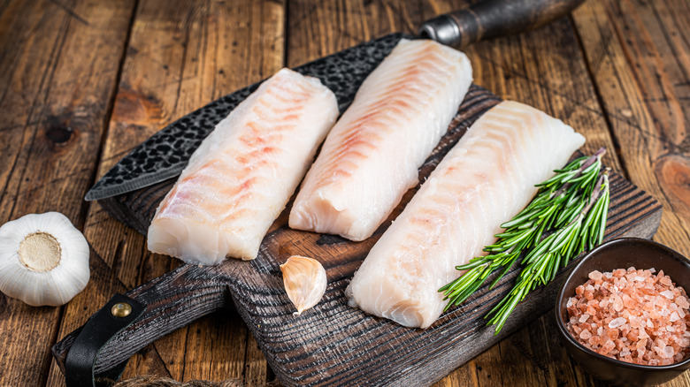 Pink cod filets on a brown wood board