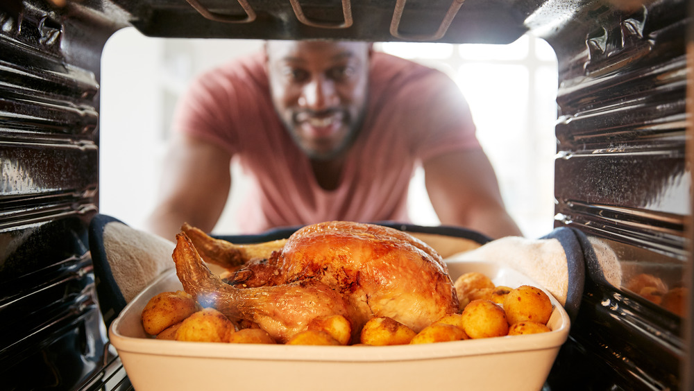 Man putting chicken in oven