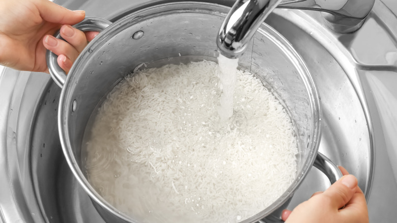 Woman rinsing rice with water under tap