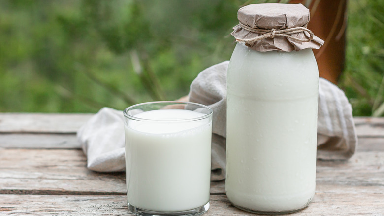 Glass jug of milk next to full glass