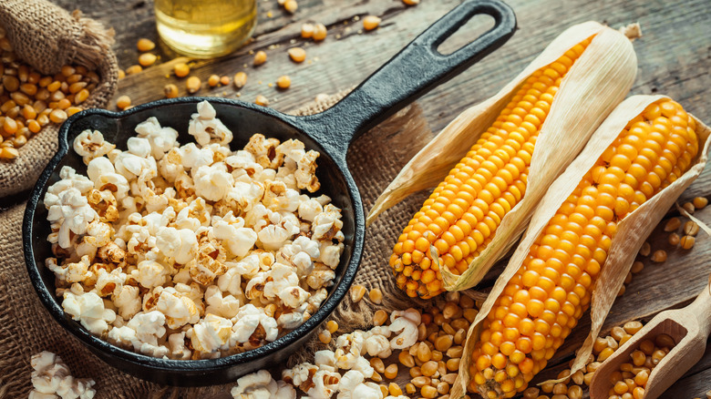 Bowl of popcorn next to two full ears of corn 