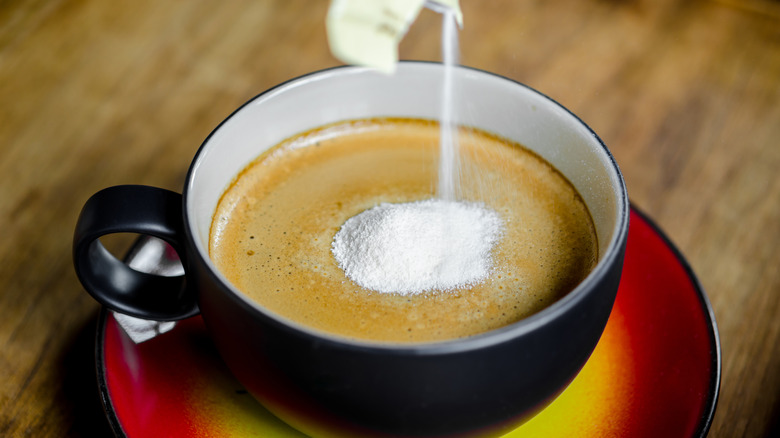 Person pouring nondairy coffee creamer into a cup 