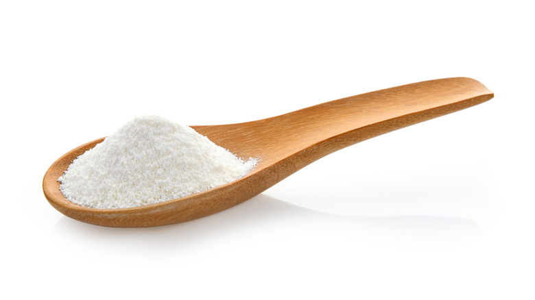 Wooden spoon with non-dairy coffee creamer on white background