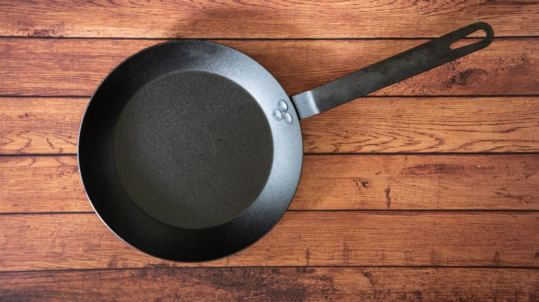 A carbon steel pan on a wooden background