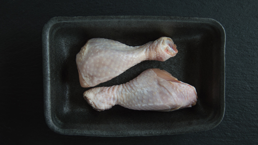 Chicken drumsticks thawing in black container