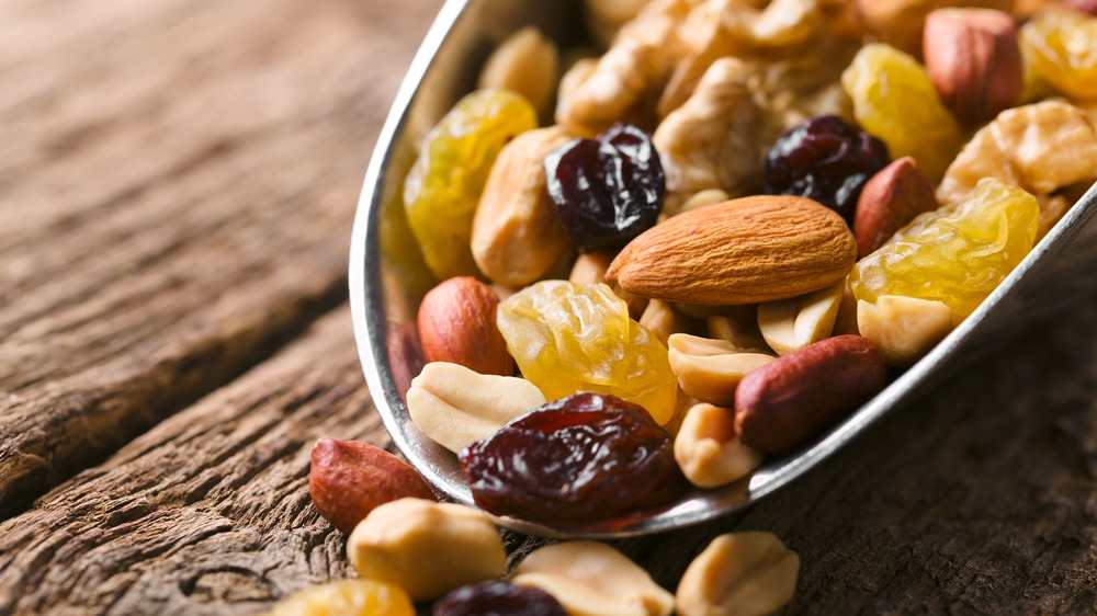 Trail mix in metal scoop on wooden table