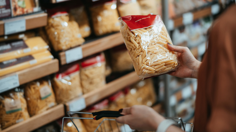 shopper looking at bag of pasta in grocery store