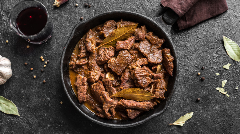 Meat stew served in a cast iron skillet with bay leaves