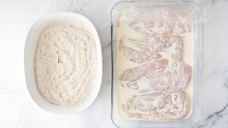 Flour mixture next to chicken marinating in buttermilk