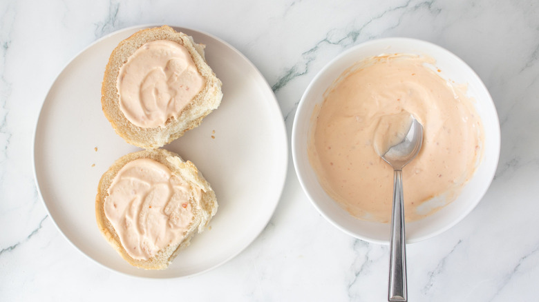 Sauced burger buns next to bowl of sauce