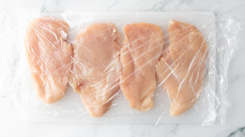 Pounded chicken breasts under sheet of plastic